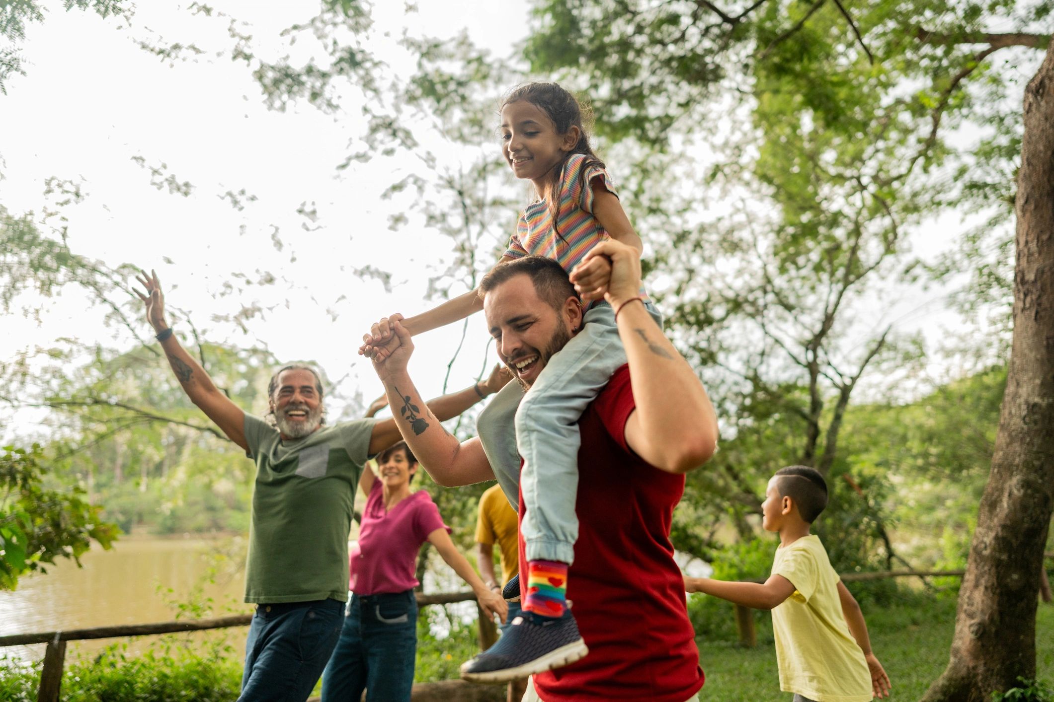 Step-father having fun during piggyback with adopted daughter in a public park